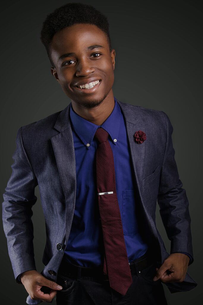Portrait of a smiling young black man in a stylish suit with a confident pose.